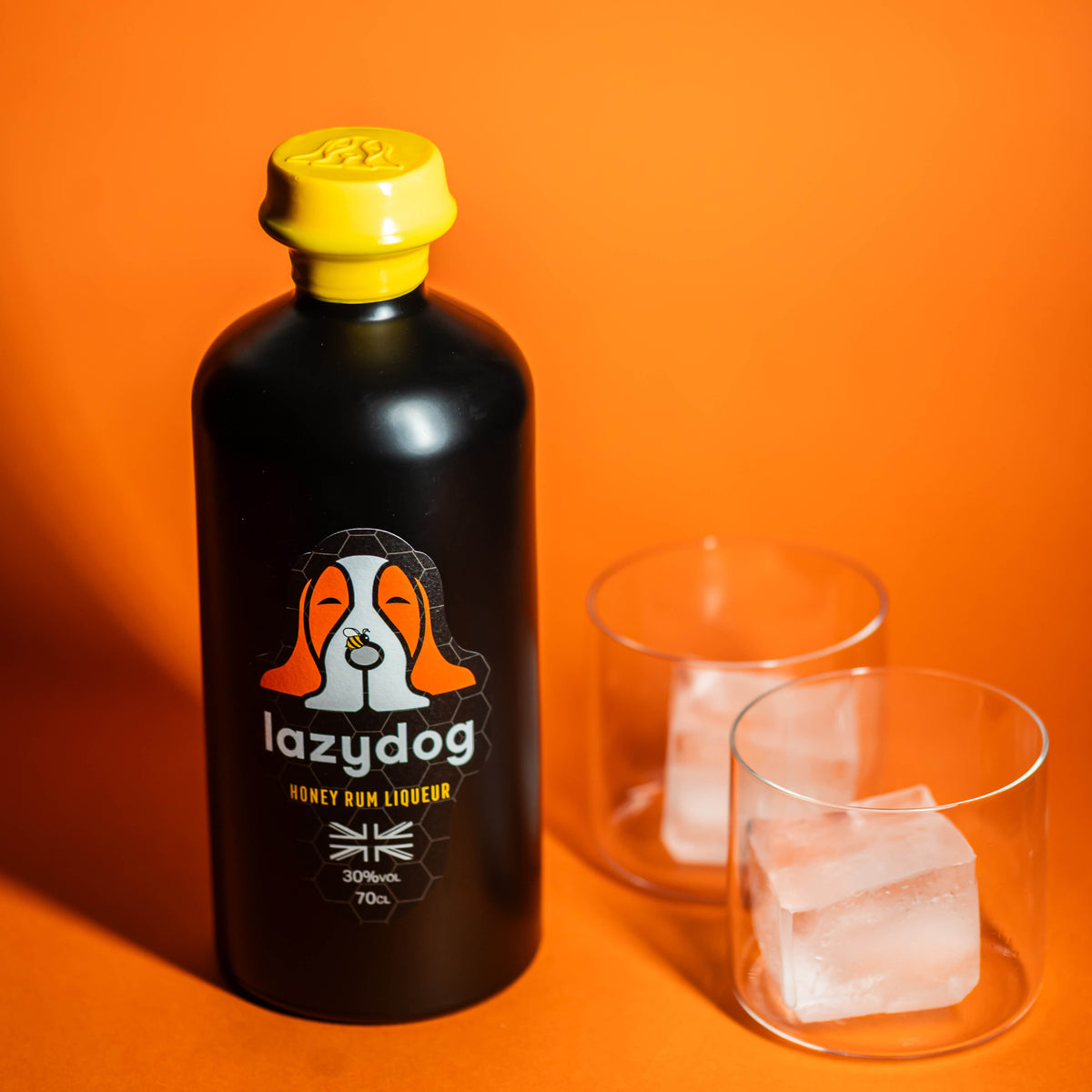 Current Lazydog Honey Rum Liqueur bottle with yellow wax and glasses